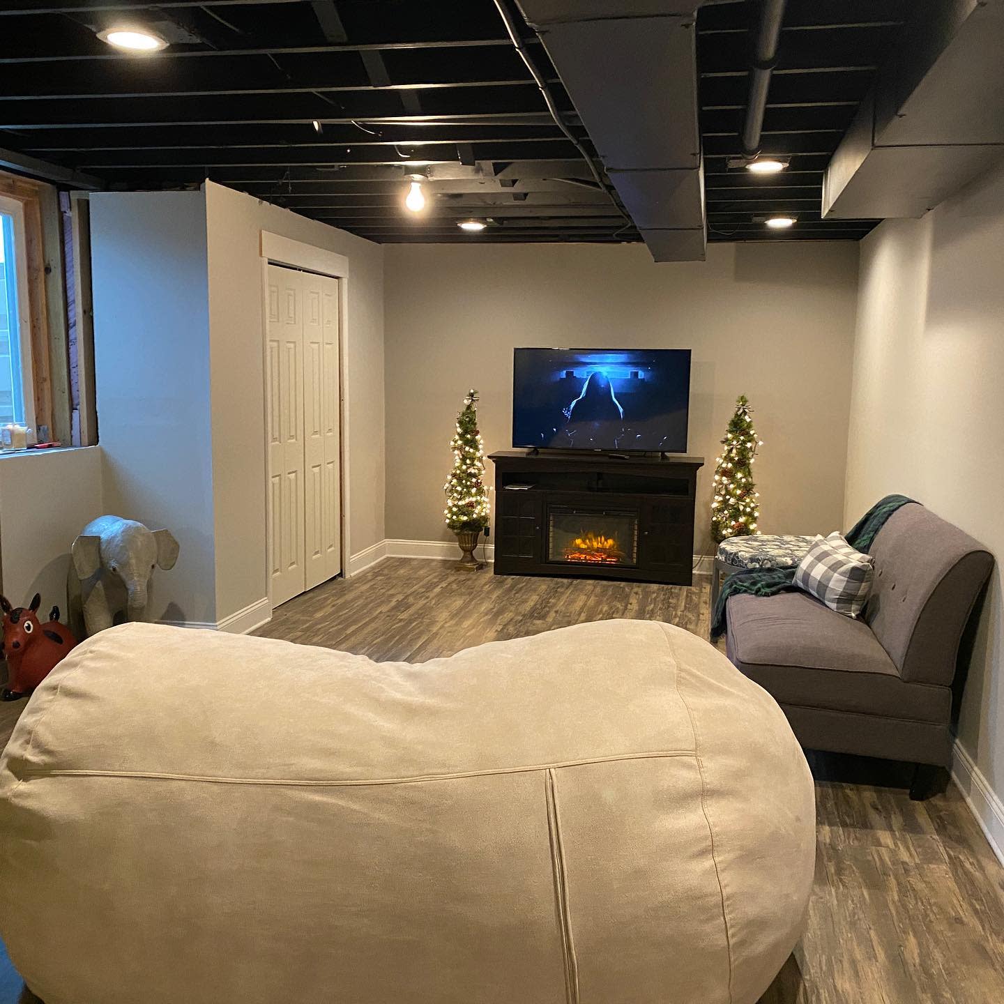 Inviting basement living room with cozy seating, electric fireplace, and holiday decor.